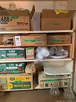 Shelf with several boxes containing canning jars and supplies including Bernardin and Mason jar boxes, and small canning and candy making supplies.