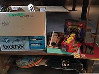 Box labeled 'Games + Art Supplies' holding various games and art supplies including puzzle and cards.