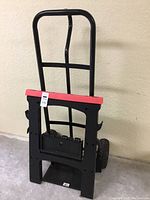 Heavy-duty black metal hand truck with saw horse clipped in front, showing red top and black body of saw horse.