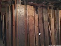 Stack of vertical wood boards of varying widths leaning against a wall