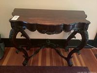 Front view of the carved side table showing full apron and leg design.