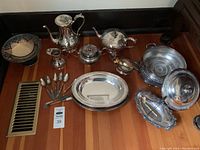 Overview photo showing all silver plated serveware pieces on hardwood floor.