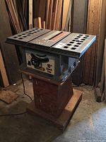 Side angle view of TradeMaster 10 inch bench saw mounted on a custom wooden stand, showing saw table top and surrounding wood.