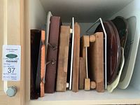 Wooden cutting boards and trays standing upright inside a cabinet.