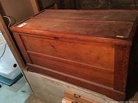 Front photo of the rectangular vintage wooden trunk with solid wood panels and metal corner and side reinforcements. Shows overall condition and finish.