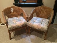 Two wicker side chairs side by side with cushions attached