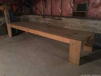Full length view of the large wooden bench in basement, showing natural wood finish and sturdy construction.