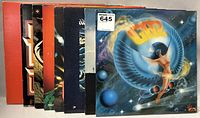 Photo showing several vinyl record album covers stacked, featuring a colorful Gaz album cover with a stylized figure and cosmic theme