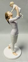 Side view of Royal Doulton porcelain figurine showing mother lifting baby