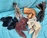 Five pairs of vintage ladies boots in various colors and styles arranged on a blue fabric background for the lot overview.