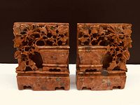 Front view of both hand carved Chinese hard stone bookends showing the detailed floral and pot carving in reddish stone.