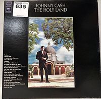 Front cover of Johnny Cash The Holy Land vinyl record showing artist and title with image of Johnny Cash and a building.
