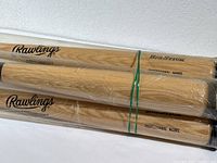 Photo showing four Rawlings wooden baseball bats bundled together with green rubber bands and wrapped in plastic.
