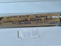 Full view of bat in protective wrap showing barrel signatures and seller’s handwritten player list note beneath.