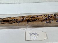 Photo of the bat showing multiple player signatures in blue ink including Tito Fuentes and others.
