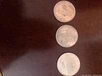 Reverse side of three Canadian silver dollar coins showing their distinct designs depicting a ship, a totem pole for British Columbia, and a 1983 symbol