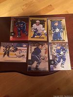 Front view of six Toronto Maple Leafs hockey cards displayed on wood surface, showing players in various poses.