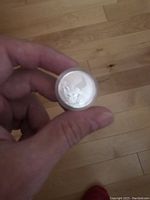 Hand holding silver Superman collectible coin in clear plastic holder, showing detailed Superman raised figure design on the coin face.