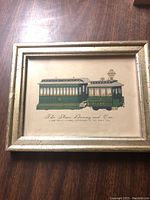Front view showing the framed vintage print of two green and beige streetcar railway cars titled "The Steam Dummy and Car."