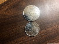 Obverse and reverse sides of the two commemorative coins showing text and images including shields and portraits.