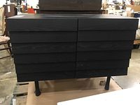 Front view showing slatted drawer‐style front panels and four cylindrical legs