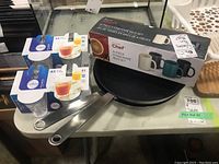 View of all items in the lot: two sets of Duralex glasses, Masterchef mug set in box, and two IKEA frying pans.