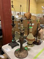 Six lamp bases on table showing varying materials and styles, details of bases visible.