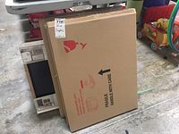 Photo showing multiple factory sealed dry erase boards and other office supplies stacked together, including cardboard boxes with fragile handling instructions.