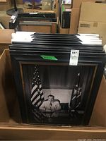 Box containing multiple framed black and white photographic prints stacked vertically