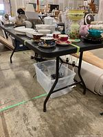 Side view of the black folding table showing scratches and table contents (not included).