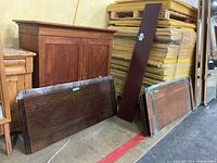 Six individual wooden table leaves leaning against furniture and packing materials