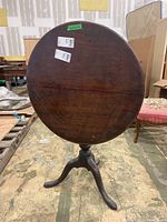 Round wooden tabletop tilted upright showing wear and scratches.