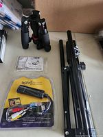 Lot displayed showing two black foldable tripods, Easy Capture USB video adapter in packaging and instruction manual.