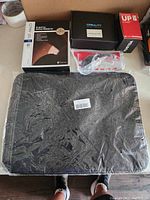 Black Nalkey laptop case wrapped in plastic with boxed Creality motherboard, Lenovo UP AC adapter, computer fan, and SRAM mount on a table.