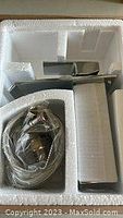 Overview of the kitchen faucet, including spout, handle, and hose assembly inside Styrofoam packaging.