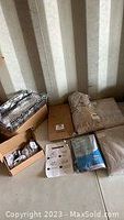 Photo showing boxed and packaged household items including shower hooks and boxed curtains.