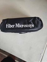 Soft black zippered carrying case with 'Fiber Microscope' printed in white