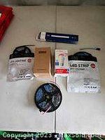 Lot contents with two LED strip light sets, one Sengled LED light box, one RGB smart bulb box, and one USB rechargeable bulb box spread on a surface.