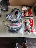 Photo showing 4 pairs of ski goggles in plastic bags, two Vurka shoe holsters in original packaging, and a metal carabiner.