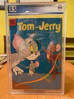 Front cover of the graded Tom and Jerry Comics #123 showing the colorful cover art of Tom and Jerry with fishing poles, protected in a hard case.