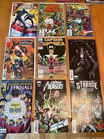 Overview photo of 9 Marvel comic books arranged in three rows on a wooden surface.