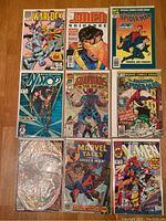 Top view of 9 Marvel comic books laid out on wood floor including Marvel Warlock, X-Men Universe, Spider-Man, Namor, Guardians of the Galaxy, Marvel Tales, and others.