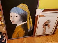 Framed reproduction painting of Girl with a Pearl Earring showing a woman with a blue headscarf and yellow clothing on black background.