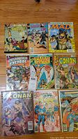 All nine comic books laid flat on a wooden surface showing covers.