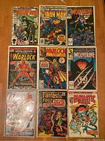 Nine Marvel comic books arranged on a table featuring Warlock, Wolverine, Iron Man, and Fantastic Four titles