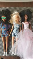 Three Barbie dolls lying side by side showing hairstyles and outfits