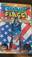 Cover of American Flagg! issue #1 showing a man holding a torn American flag with stars and stripes background.