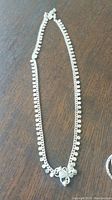 Silver-tone chain necklace featuring small round charms along the chain with a central decorative charm.