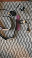 Two Fitbit charging cables with attached plugs, an extra purple silicone band, and two Fitbit bands - one black perforated and purple silicone band on a textured surface.