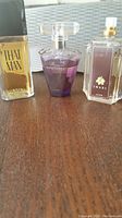 Photo of three fragrance bottles side by side: Revlon That Man, Avon Rare Amethyst, Avon Imari without cap, showing label and fill level.